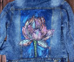 a denim jacket with a flower painted on it