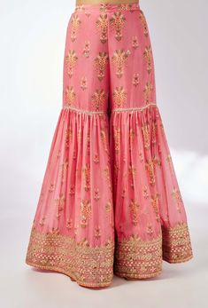 This pretty ensemble of floral jaal, with intricate border embroidery. The sleeveless kurta is embellished down the front and tried with a smart pleated magzi to finish the neckline and armhole. The flowing sharara bottom with gota embroidery still has a lot of flounce and flow. Pink Sharara With Dori Work, Diwali Sleeveless Palazzo Set With Chikankari Embroidery, Pink Sleeveless Semi-stitched Anarkali Set, Festive Sleeveless Palazzo Set With Chikankari Embroidery, Traditional Sleeveless Sharara With Chikankari Embroidery, Pink Sleeveless Salwar Kameez With Resham Embroidery, Pink Sleeveless Sharara For Navratri, Sleeveless Sharara With Chikankari Embroidery For Festivals, Sleeveless Embroidered Sharara For Eid