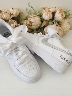 a pair of white sneakers with a bow on the side and flowers in the background