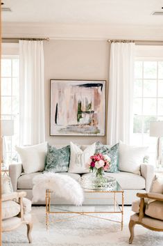 a living room filled with lots of white furniture and decor on top of a rug