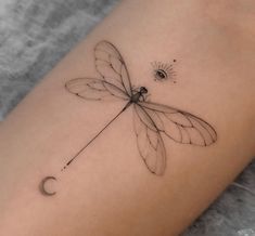 a small dragonfly tattoo on the arm and leg, with an eye in the background