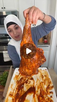 a woman holding up a large piece of meat