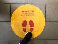 a person standing in front of a sign that says thank you for practicing social distancing