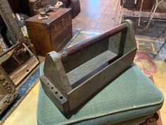 an old wooden box sitting on top of a green cushion next to other antique furniture