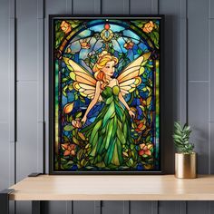 a stained glass window with a fairy holding a flower in front of it on a shelf