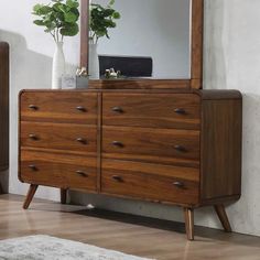 a wooden dresser sitting next to a mirror and potted plant on top of it