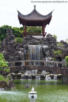 a white fire hydrant sitting in front of a small waterfall next to a building