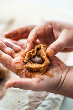 two hands are holding something that looks like food in the palm of someone's hand