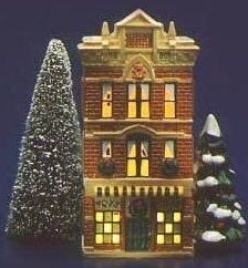 a small christmas tree next to a toy house with lights on and trees in front