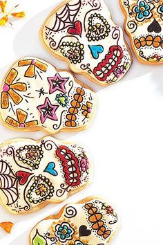 decorated sugar cookies arranged in the shape of skulls on a white surface with autumn leaves