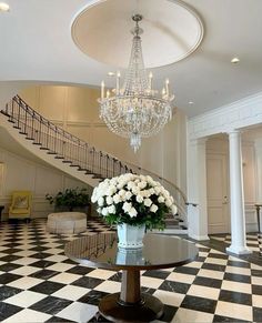 a chandelier hangs from the ceiling above a table with white flowers in it