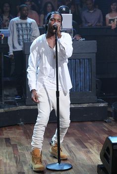 a man standing in front of a microphone on top of a wooden floor