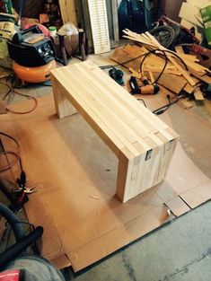 a wooden bench sitting on top of a hard wood floor next to a pile of tools