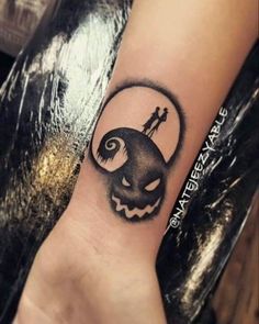 a black and white tattoo on the wrist of a person with a jack - o'lantern