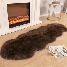 a large brown sheepskin rug sitting on top of a hard wood floor next to a fire place