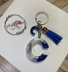 a keychain with a blue tassel hanging from it's side on top of a piece of paper