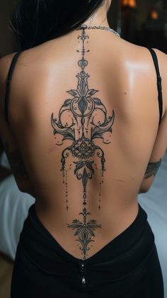 the back of a woman's body with an intricate tattoo design on her lower back