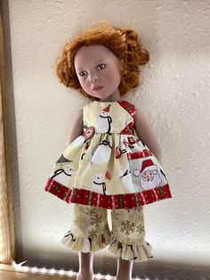 a doll with red hair wearing a white dress and matching shoes is standing in front of a wall