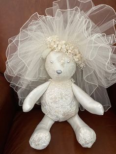 a white stuffed animal with a veil on it's head sitting on a couch