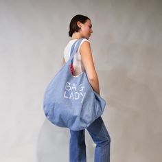 The bag Lady denim bag from L&N is your new best friend. Fill this bag with your life’s belongings and there will still be room for more! Lined with a fun cotton print this gutsy bag has been hand painted by us with a fun slogan and we’ve even included an inside zip pocket for your phone, your keys and your favourite lippy!! Take to the beach or to your next weekend getaway.  Please note print may vary between the Paisley or Hearts. 100% Cotton, Made from dead stock repurposed denim.  Cool Gentl Trendy Denim Bags With Dust Bag Included, Denim Blue Canvas Shopping Bag, Trendy Denim Blue Travel Bags, Denim Travel Tote Bag, Denim Blue Cotton Bags For Everyday Use, Denim Blue Cotton Bag For Daily Use, Denim Blue Cotton Shoulder Bag For Travel, Casual Denim Shoulder Bag With Dust Bag, Blue Denim Bag With Dust Bag Included