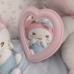 two stuffed animals sitting next to each other on a bed with a heart shaped frame