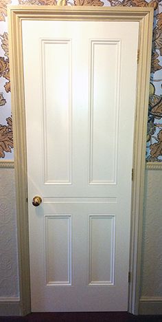 a white door in a room with wallpaper