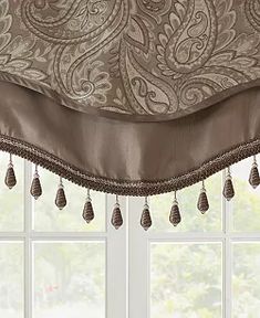 a window with a curtain that has tassels hanging from the top and bottom