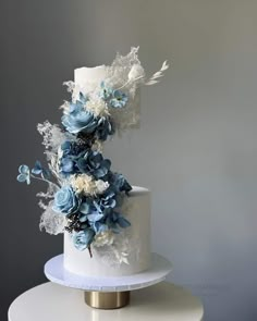 a white and blue wedding cake with flowers on top