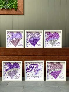 four purple and white framed pictures with the letter m on them in front of a wooden bench