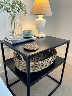 a black table with a basket on it and a lamp next to it in the corner