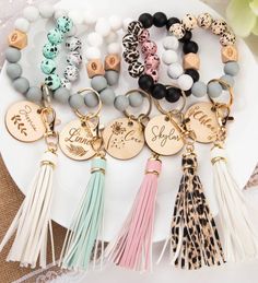 the personalized bracelets with tassels and charms are displayed on a plate