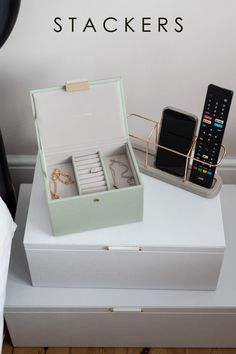 an open box with jewelry and a remote control sitting on top of a white table