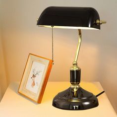 a desk lamp sitting on top of a white table next to a framed picture and an antler's head