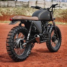 a black motorcycle parked on top of a dirt field