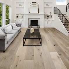 a living room filled with furniture and a fire place next to a staircase leading up to a second story window