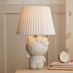 a hello kitty lamp sitting on top of a table next to a clock