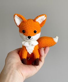 a hand holding a small knitted fox