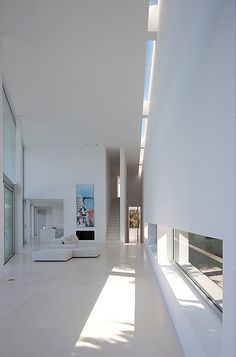 the interior of a modern house with white walls and floor to ceiling windows that are open