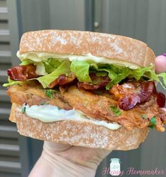 a person holding up a sandwich with bacon and lettuce