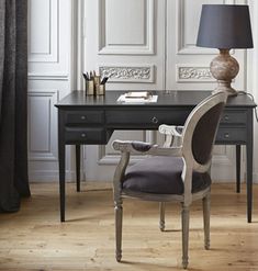 a desk with a lamp and chair in front of it on a hard wood floor