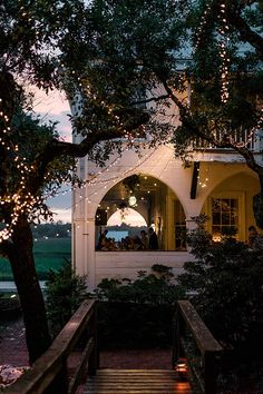 an outside view of a house with lights on the porch and stairs leading up to it