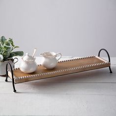 a tray with two teapots and a potted plant