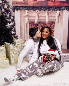 a man and woman are kissing in front of a christmas tree