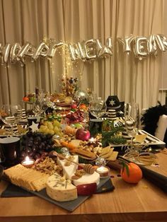 a wooden table topped with lots of cheese and fruit next to a sign that says happy new year