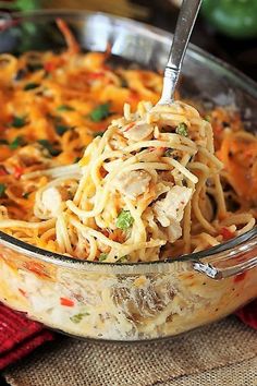 a spoon full of noodles and chicken in a casserole dish