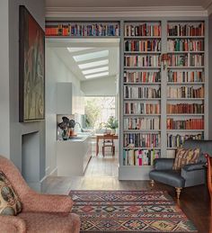 a living room filled with lots of furniture and bookshelves covered in colorful books