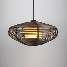 a light hanging from a ceiling fixture made out of wood and wicker with a yellow light in the center