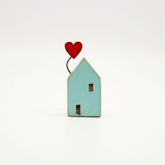 a small blue house with a red heart on it's roof is shown in front of a white background