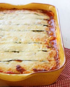 a casserole dish with zucchini in it on a red and white checkered table cloth