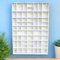 a white book shelf sitting next to a potted plant